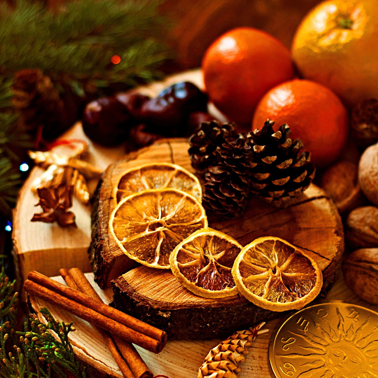 Dried orange slices, pine cones, cinnamon sticks, and fresh fruits arranged on wooden board with holiday decorations