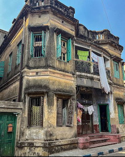 Aged colonial building corner in Kolkata with turquoise shutters and weathered facade