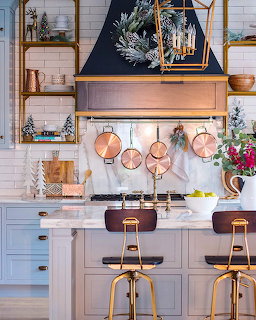 Festive kitchen with copper cookware, blue cabinets, white tile, and Christmas greenery