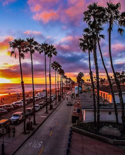 Sunset over palm tree-lined coastal street in Oceanside, California with colorful sky