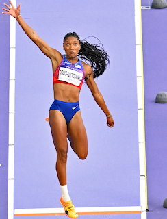 Female athlete soaring through the air during a long jump event at an indoor track competition