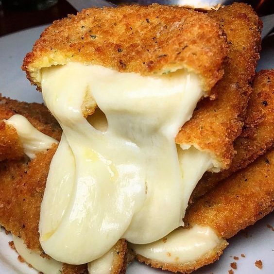 Close-up of fried mozzarella sticks with melted cheese stretching out