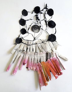 Handmade wall hanging with black yarn circles and clipped pink and orange fabric strips