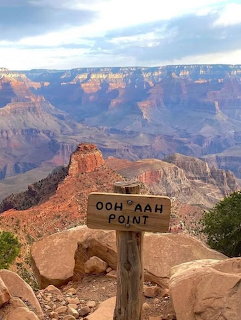 Wooden Ooh Aah Point sign overlooking red rock cliffs and layered canyon walls at the Grand Canyon