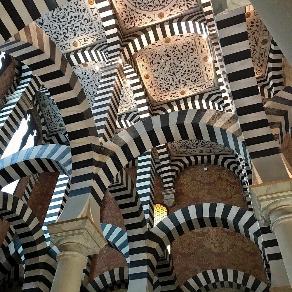 Interior view of Rocchetta Mattei castle showing bold black and white striped arches and ornate tilework
