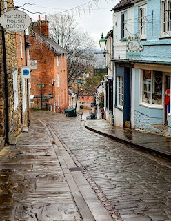 Wet cobblestone street on Steep Hill in Lincoln with old buildings and a lamp post