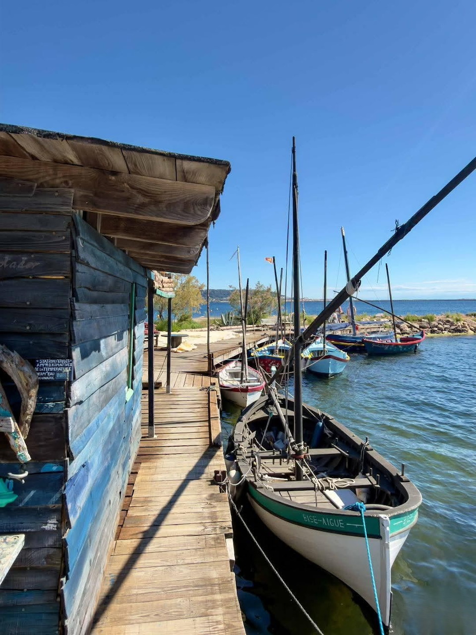Wooden boats docked by a rustic cabin on a wooden pier under blue sky