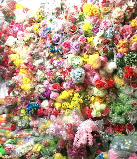 Dense wall of colorful artificial flower bouquets wrapped in plastic at flower market