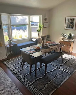 Bright living room with a bay window seat, coffee table, rug, and sunlight on the wooden floor
