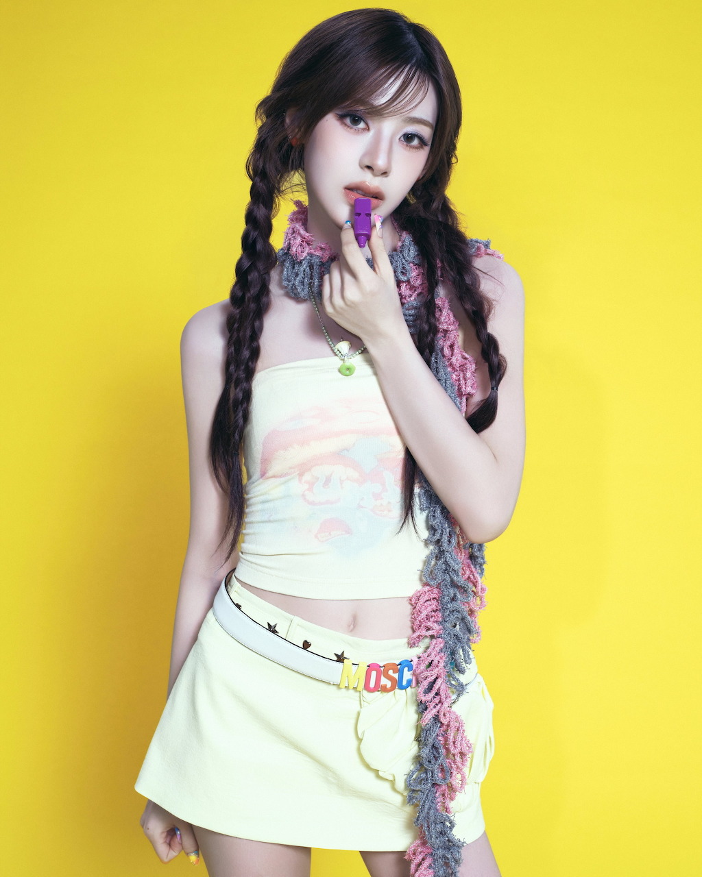 Young woman with long black braids in white outfit posing against yellow background