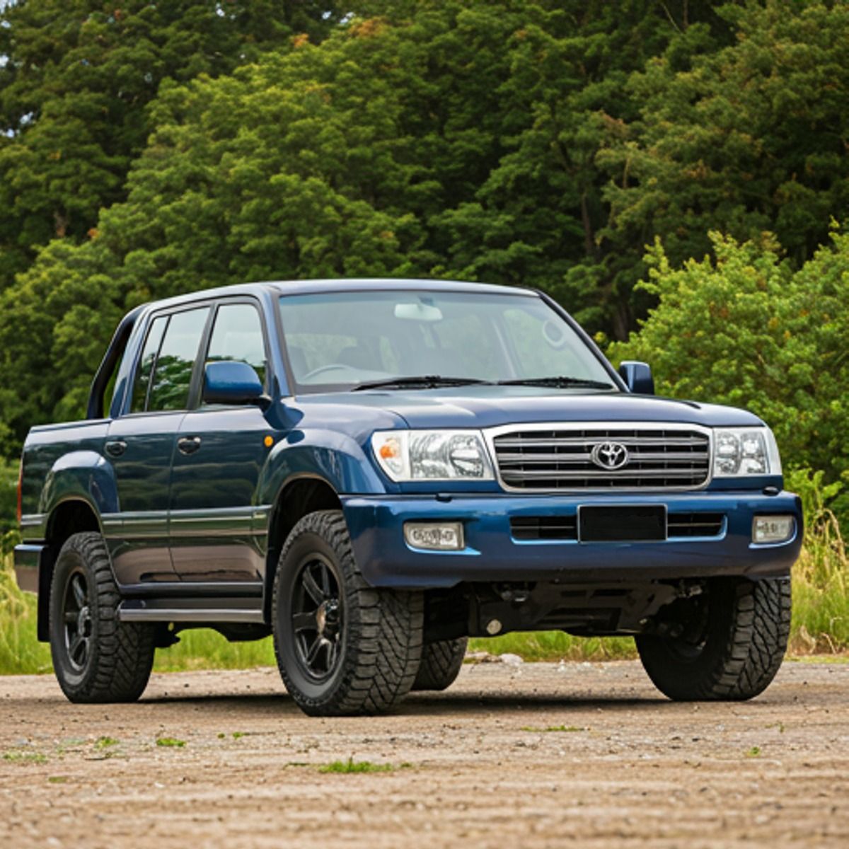 Blue Toyota pickup truck parked on dirt with trees behind it