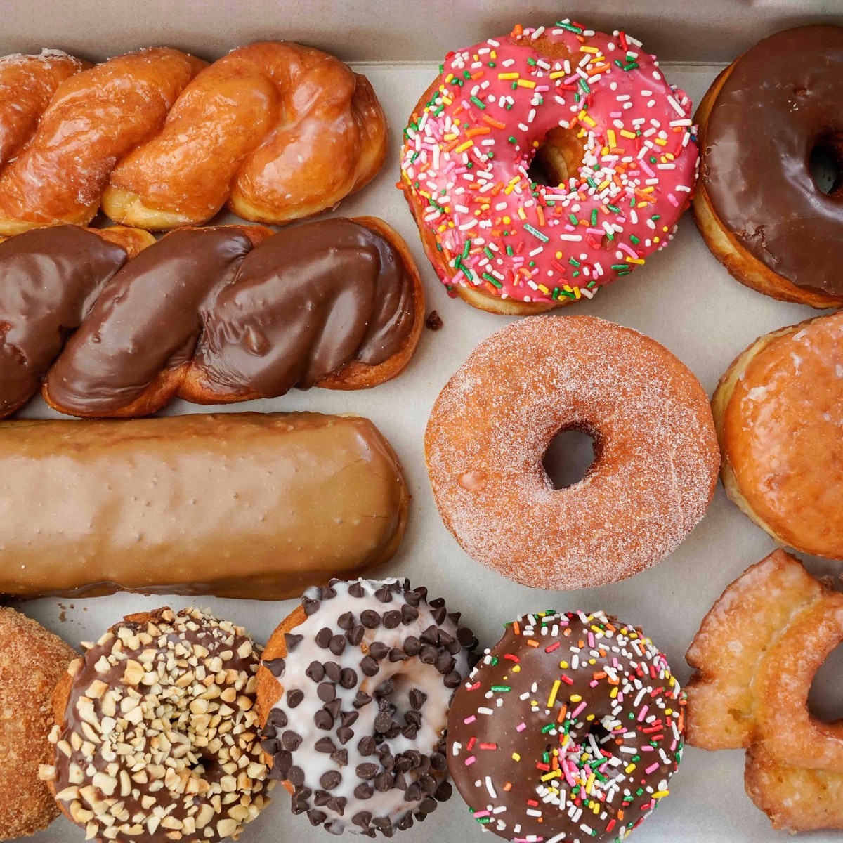 Assorted donuts with different glazes and toppings arranged on white background