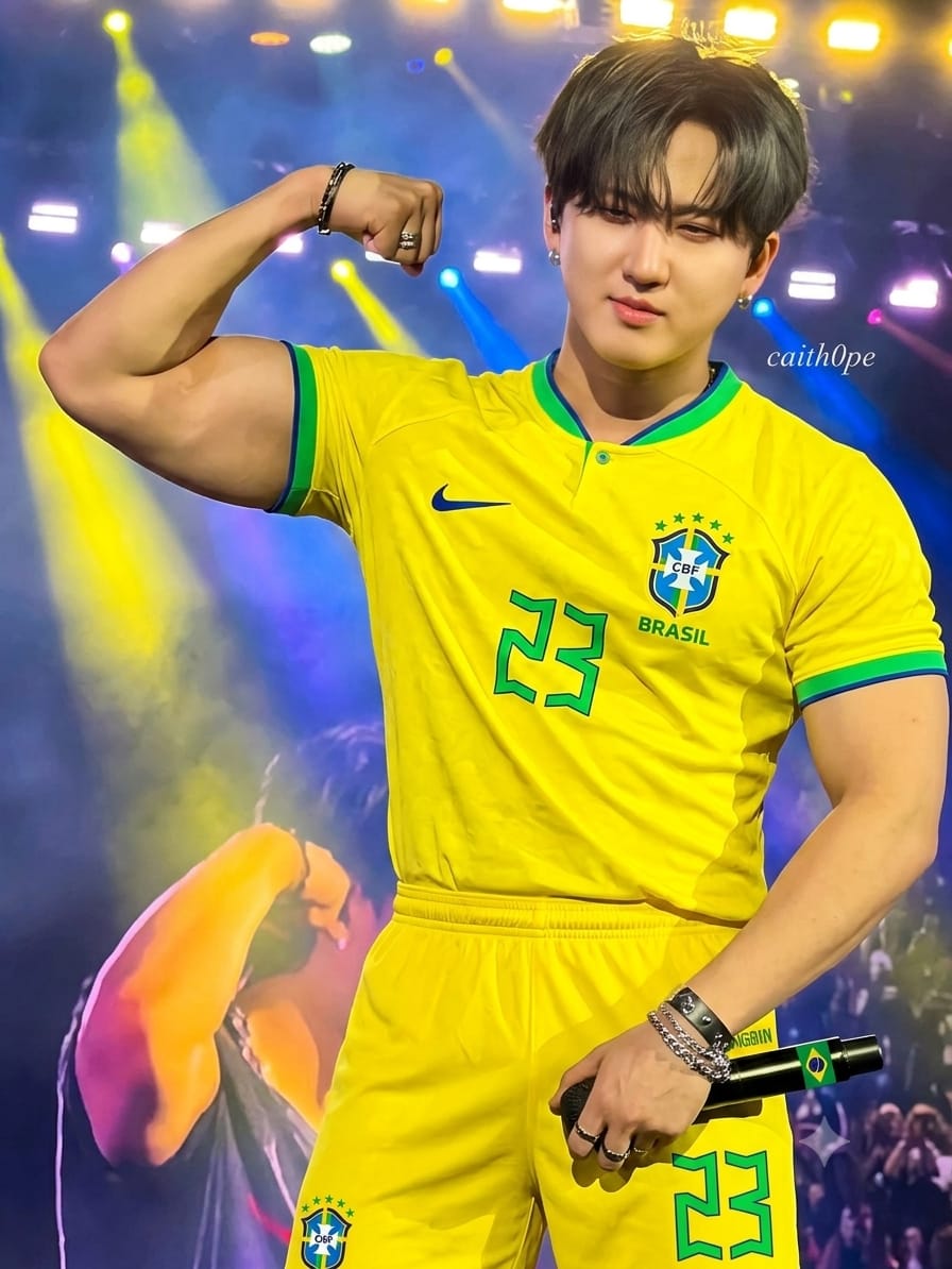 Male performer in a yellow Brazil jersey flexing on a concert stage