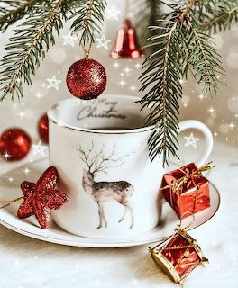 Christmas coffee mug with reindeer, red ornaments, pine branches, and gift boxes on white plate