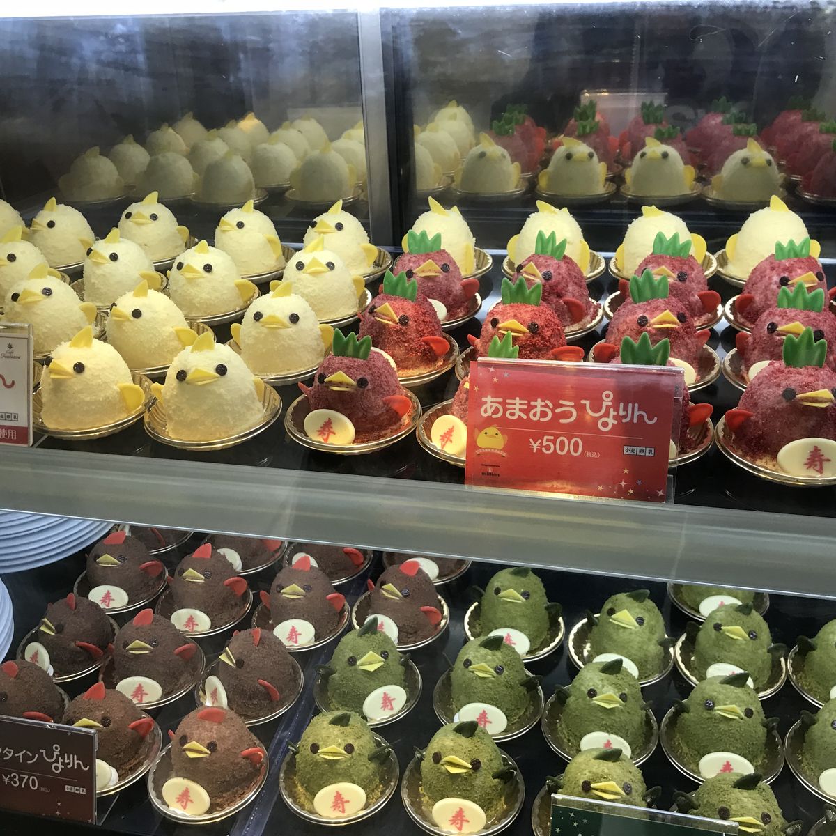 Display case showing rows of yellow chick-shaped desserts and strawberry sweets in a Japanese bakery