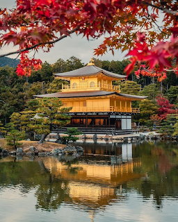 Golden Pavilion temple in Japan with red maple trees and pond reflection