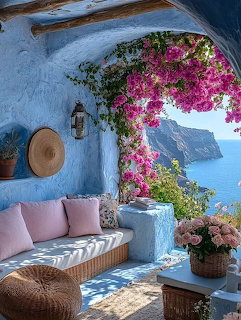 Whitewashed Greek-style terrace with pink bougainvillea, cushions, and a blue sea cliff view