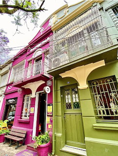 Colorful street with a bright pink building beside a green building with iron balconies and ornate doors