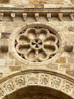 Close-up of a carved stone rose window above an ornate stone arch on a historic building
