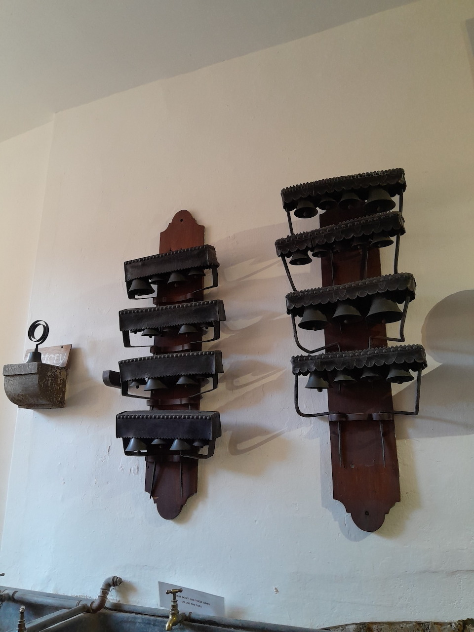 Antique flat irons on wooden wall racks in a whitewashed historic castle kitchen