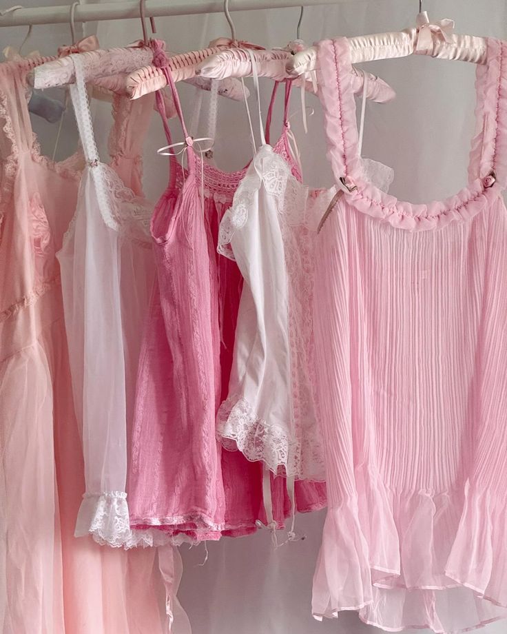 Pink and white coquette-style camisoles and tops with lace details hanging on a clothing rack