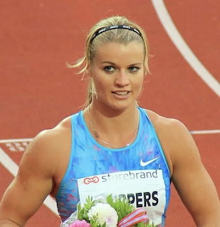 Blonde female track athlete in a blue uniform on a red running track