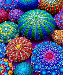 Colorful stones painted with intricate mandala and dot patterns in vibrant rainbow hues
