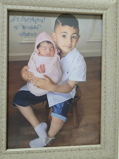 Framed portrait of a young boy holding a newborn baby wrapped in pink