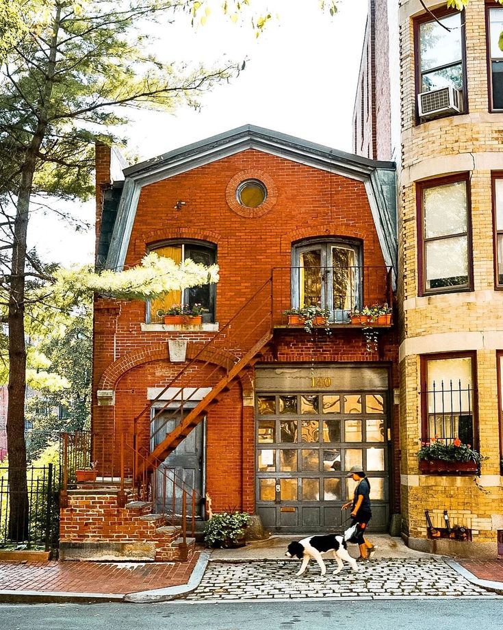 Person walking dog past red brick townhouse on cobblestone street