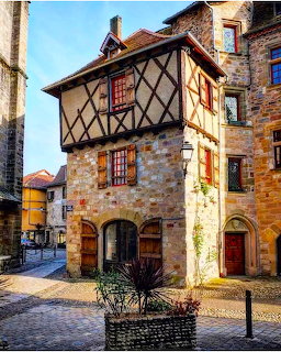 Medieval half-timbered stone building with crossed wooden beams on a coblestone street in a French village
