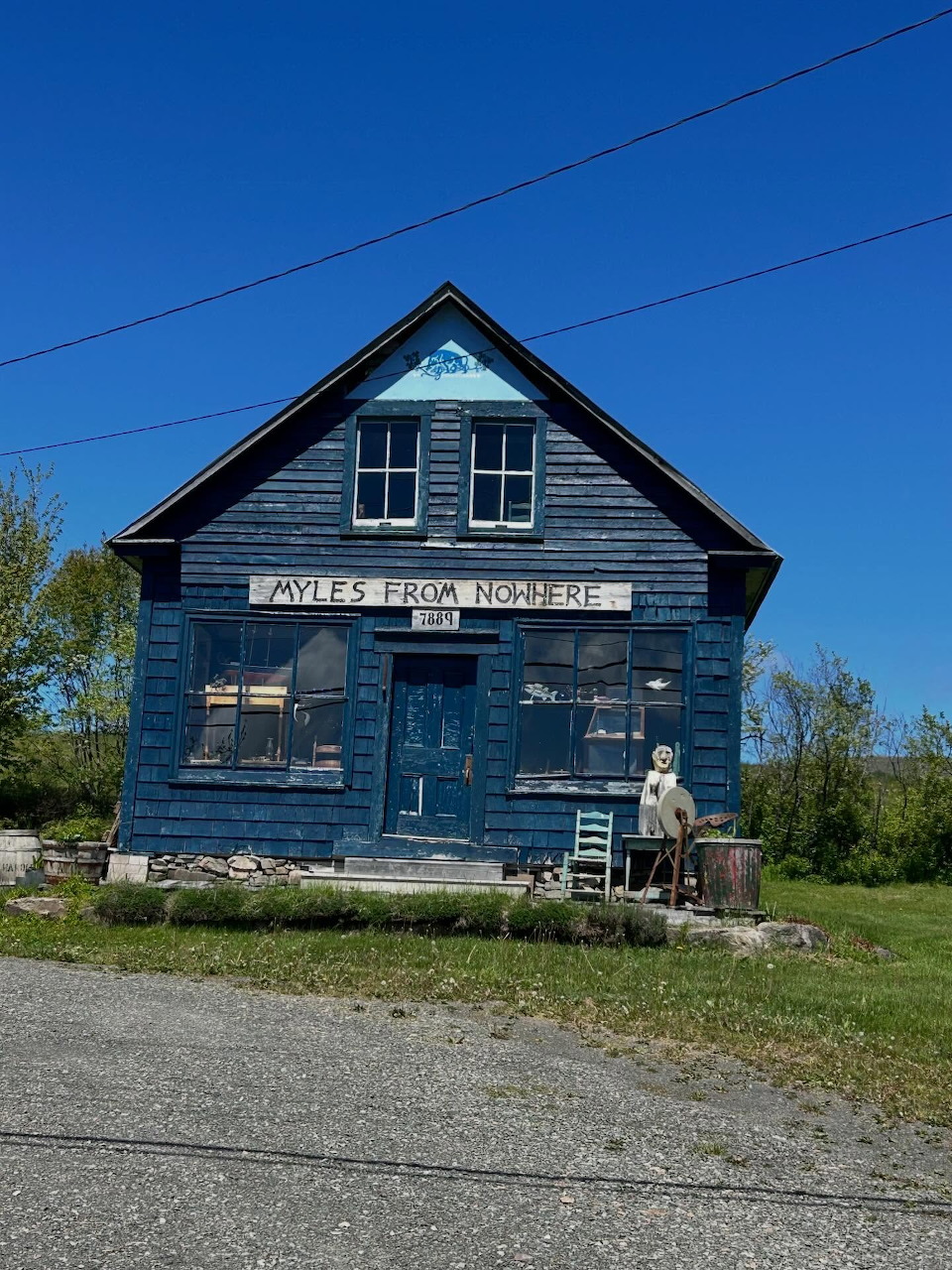 Old blue wooden general store with painted sign on rural roadside under clear blue sky