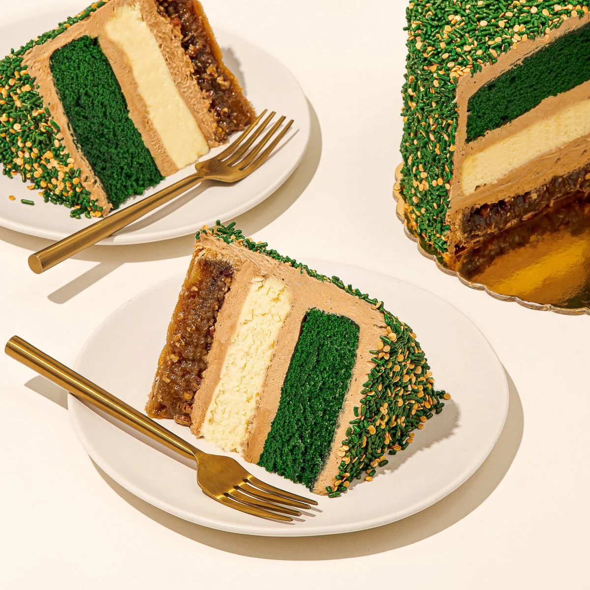 Slices of green, tan, and brown layered cake with gold sprinkles on white plates