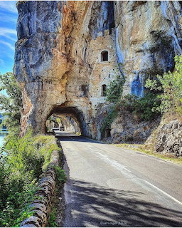 Road passing through a rock tunnel beneath Château des Anglais built into a cliff Bouziès, France