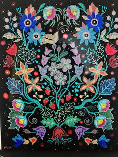 Symmetrical beadwork art with colorful flowers, deer, birds, and nature motifs on black background