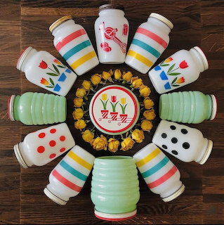 Colorful vintage salt and pepper shakers arranged in a circle around a decorative plate on wooden surface
