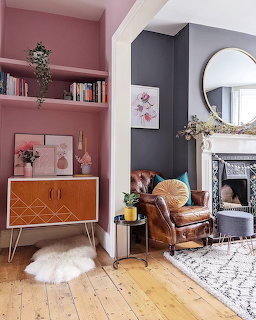 Living room with pink alcove shelving, geometric sideboard, brown leather armchair, and grey fireplace wall