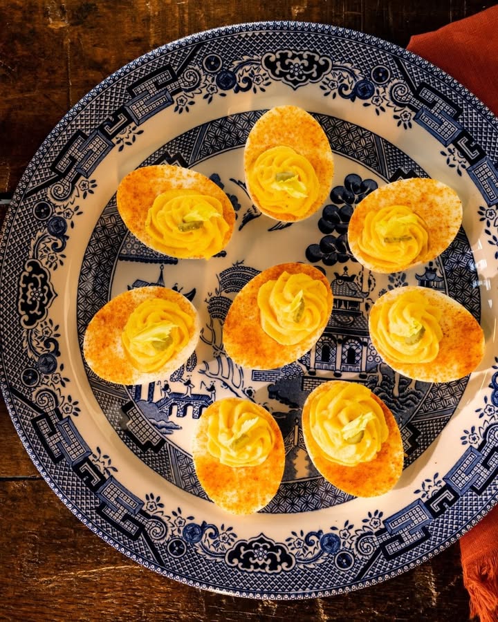 Plate of deviled eggs topped with paprika and fresh herbs
