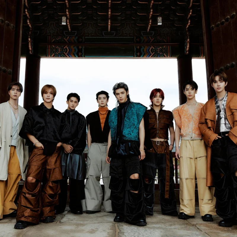 Eight young men posing in stylish clothing inside a traditional building entrance