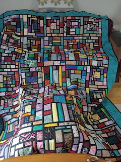 Handmade quilt with stained glass mosaic pattern in multicolored squares on turquoise chair