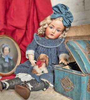 Vintage porcelain doll in striped blue dress with blonde curly hair, blue beret, holding a small teddy bear
