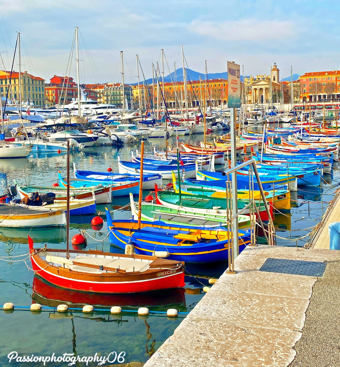 Vibrant painted boats in Nice harbor with colorful buildings along the waterfront