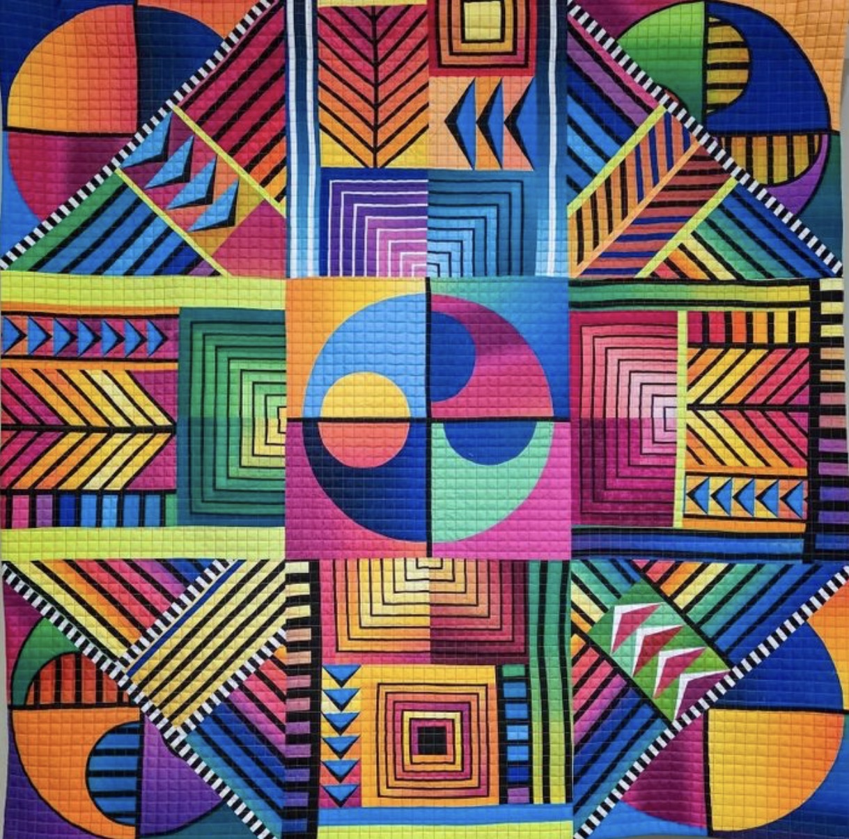 Colorful geometric quilt pattern with bold shapes and vibrant hues in grid arrangement