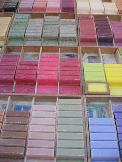 Colorful handmade soap bars arranged in rainbow gradient in wooden compartments