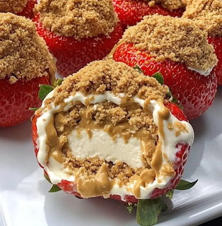 Cream cheese stuffed strawberries with graham cracker topping, one halved to show filling