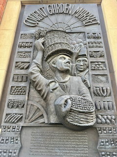Stone relief sculpture on Covent Garden Market building showing carved figures with basket and decorative border patterns