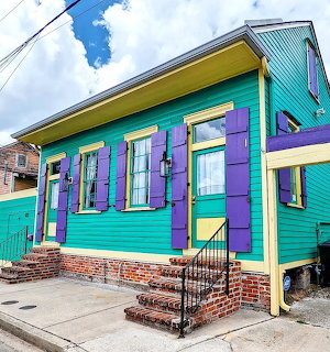 Colorful teal house with purple shuters and yellow trim on a street corner