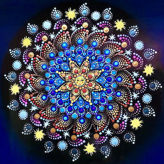 Circular mandala with intricate dot patterns in blue, yellow, pink, and white on dark blue background