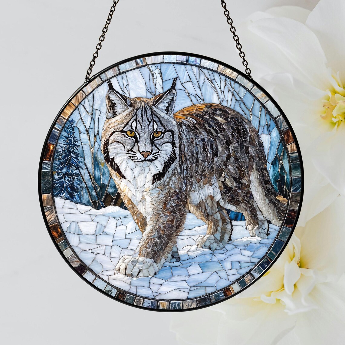 Round stained glass suncatcher with a lynx in a snowy forest hanging in front of white flowers