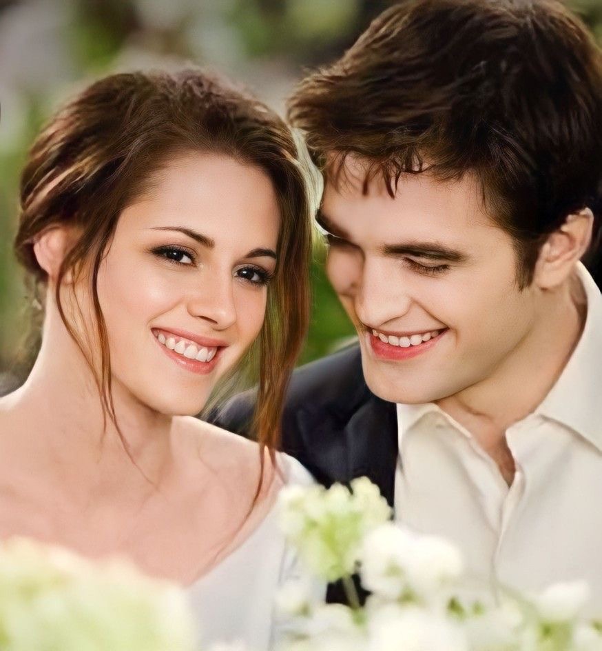 Young smiling couple posing closely together outdoors with white flowers in background