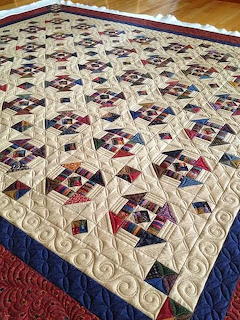 Patchwork quilt with red, blue, and cream star pattern blocks and quilted swirl designs
